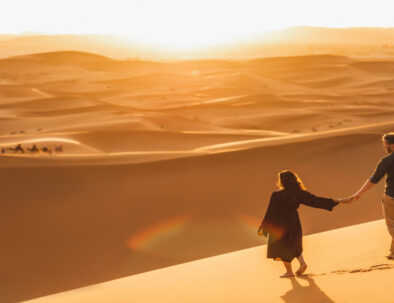 Una pareja cogida de la mano en el desierto de Merzouga feliz tras ahorrarse el viaje en Marruecos