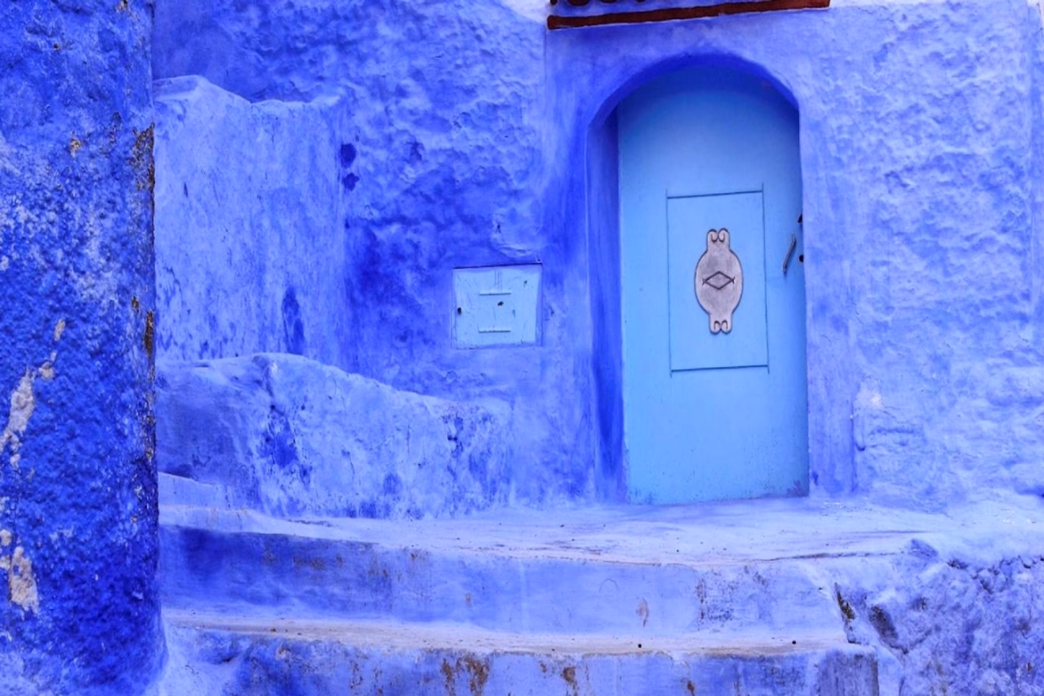 Chefchaouen, la Ciudad Azul de Marruecos, enclavada en las montañas del Rif, con sus famosas casas pintadas de azul y su medina en la ladera rodeada de exuberante vegetación.