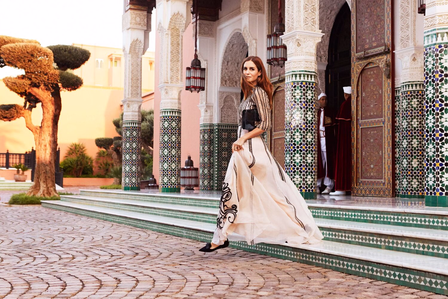 Mujer con un elegante vestido largo caminando por el patio de un riad marroquí en Marrakech, ejemplo de qué ropa llevar en Marruecos