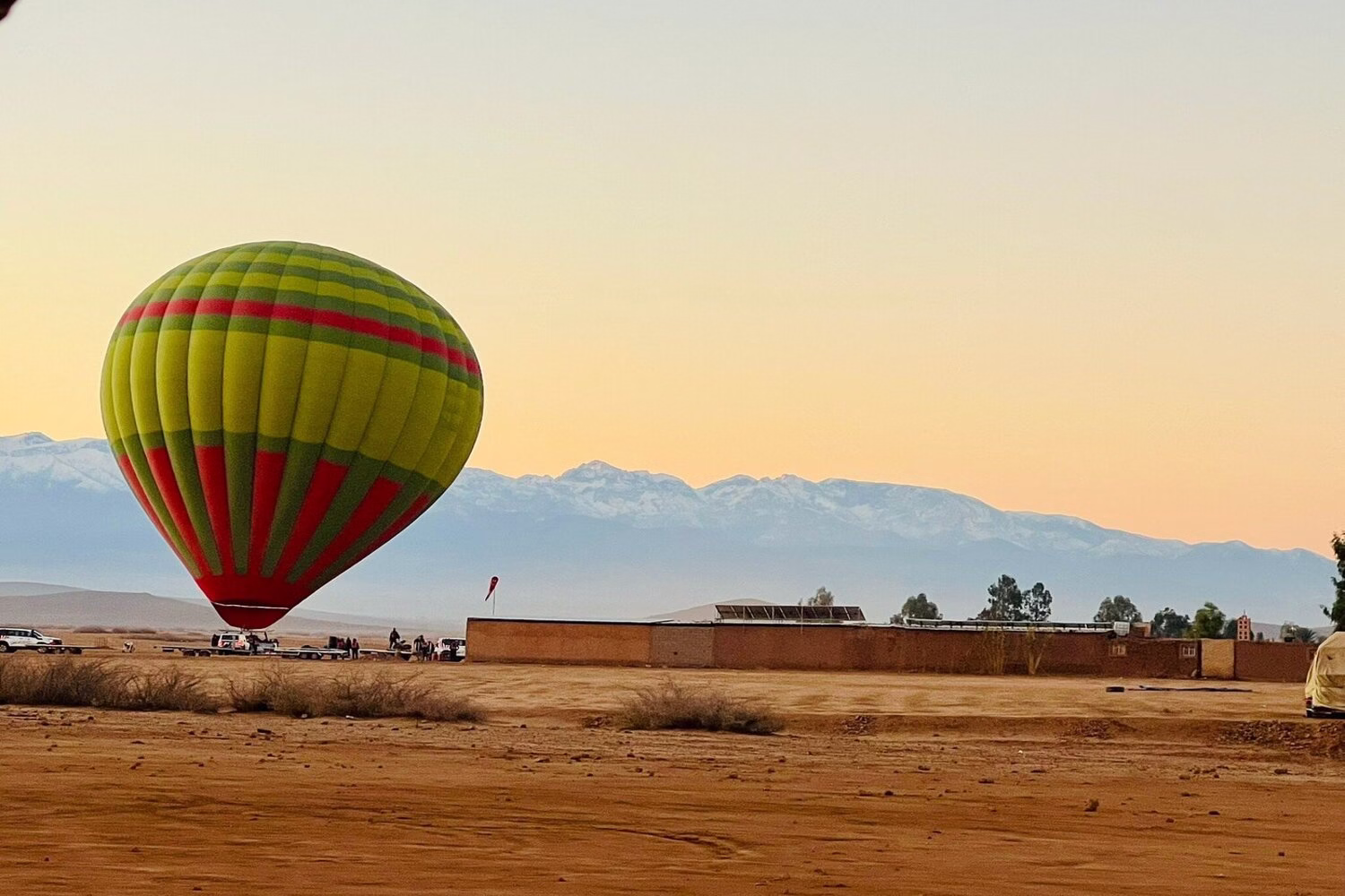 Globo aerostático al amanecer en Marrakech flotando sobre el desierto con las montañas del Alto Atlas cubiertas de nieve al fondo