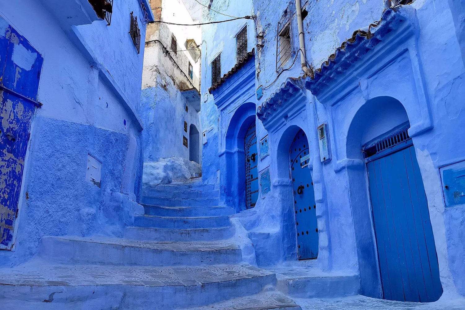 Callejón y escalones lavados en azul en la medina de Chefchaouen, una escena tranquila que ayuda a responder a la pregunta “¿es seguro viajar a Marruecos?”.
