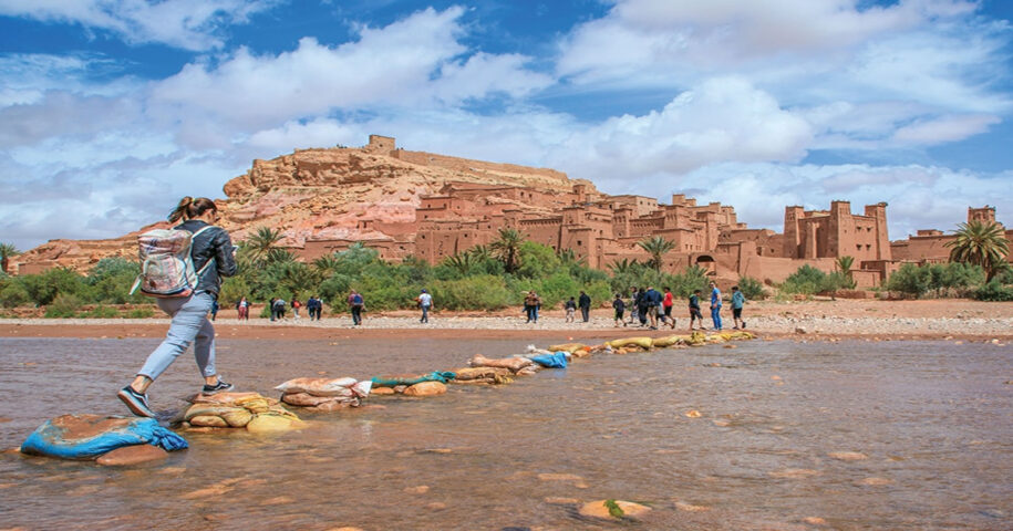 A backpacking traveler crossing the river in Morocco.